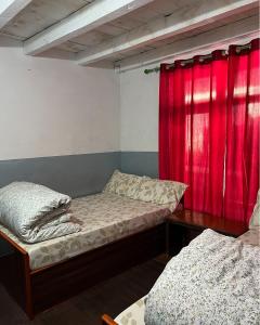 a room with two beds and a red curtain at Hotel Sakura in Jomsom