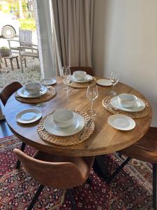 a wooden table with plates and wine glasses on it at BelleVie Apartment, Eijsden-Maastricht in Eijsden +43 photos