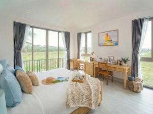 a bedroom with a bed and a desk and windows at Entire Hoi An Villas By Ovui in Hoi An