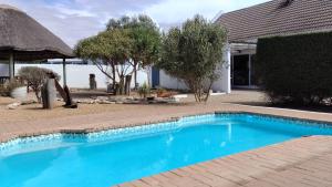 a blue swimming pool in front of a house at Anchorage in Stompneusbaai
