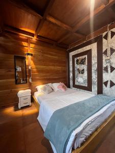 a large bed in a room with wooden walls at Cabin Hillside Dieng in Diyeng