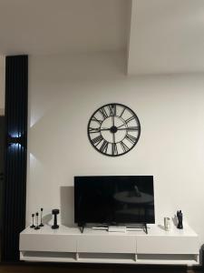 a clock on a white wall above a white table at Mirror Apartments in Petrovec