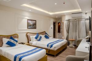 a hotel room with two beds and a chair at Hotel Smart Durbar in Dharampur +16 photos