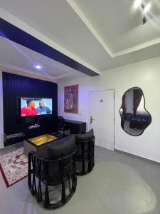 ein Wohnzimmer mit schwarzen Sesseln und einem Flachbildfernseher in der Unterkunft Rontop in Gwarinpa