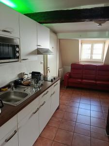 a kitchen with a sink and a red couch at Pension Webstuhl in Deizisau +10 photos
