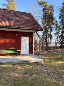 a red building with a bench next to a door at Kyrkåsen in Borgvik