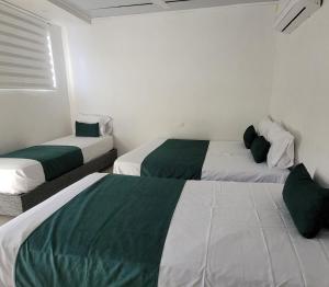 two beds in a room with green and white at Hostal Casa Marle in Puerto Colombia +3 photos