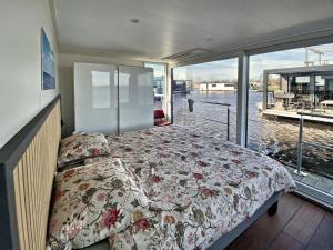 a bedroom with a bed on a boat with a balcony at Houseboat Robbedoes in Offingawier