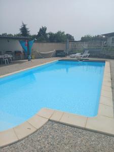 a large blue swimming pool in a yard at Chalet LALi in Saint-Étienne-de-Fontbellon
