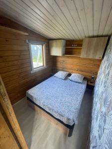 a small bedroom with a bed in a wooden cabin at Chalet LALi in Saint-Étienne-de-Fontbellon
