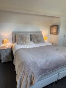 a bedroom with a large white bed with two lamps at BelleVie Apartment, Eijsden-Maastricht in Eijsden