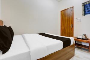 a bedroom with a white bed and a wooden door at Hotel O by OYO Saptagiri Comforts in Bangalore +21 photos