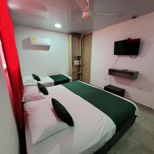 a bedroom with two beds and a flat screen tv at Hostal Casa Marle in Puerto Colombia