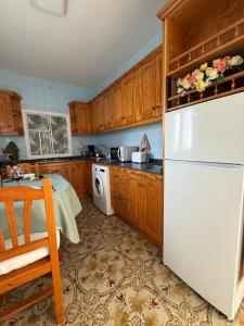 a kitchen with wooden cabinets and a white refrigerator at Nature in Tejeda 2 in Tejeda