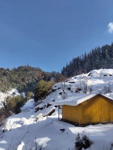 a shed covered in snow on a snowy hill at Mayadeep Resort and Hostels in Chopta
