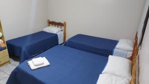 ein Zimmer mit zwei Betten mit blauen Laken und weißen Kissen in der Unterkunft Pousada Parque in Mostardas