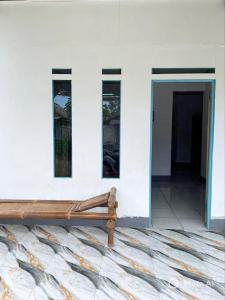 a wooden bench sitting in front of a white building at Tiga Dara Homestay 3 in Pangandaran
