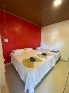 two beds in a room with a red wall at Pousada da Mangueira 1 in Barreirinhas +38 photos