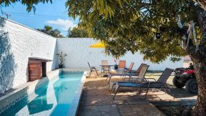 a swimming pool with chairs and a table next to a house at Pousada da Mangueira 1 in Barreirinhas