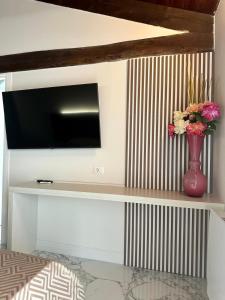 a tv on a wall with a vase with flowers at Il Casale della Baronessa in Palmi
