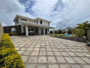 a large white house with a driveway at Skyra Villa in Mahébourg