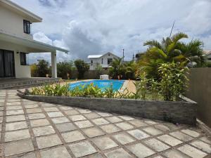 a backyard with a swimming pool and a house at Skyra Villa in Mahébourg +4 photos