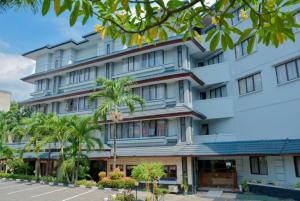 a building with palm trees in front of it at Citra Boutique Hotel Cikarang in Cikarang