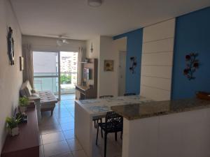 a kitchen and living room with a table and a couch at Apartamento 500m Praia da Enseada Guarujá varanda e vaga de garagem in Guarujá