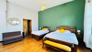 a bedroom with two beds and a green wall at 1825 Hotel in La Paz