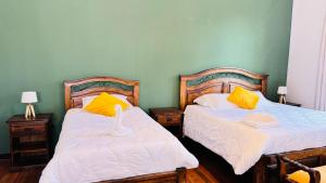 a bedroom with two beds with yellow and white sheets at 1825 Hotel in La Paz