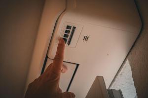 a person reaching up to an air conditioner on a ceiling at Haus am Stausee in Altenbeuthen