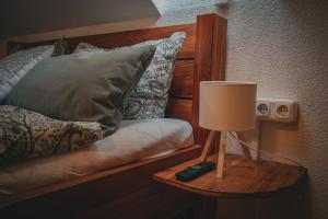 a lamp on a table next to a bed with pillows at Haus am Stausee in Altenbeuthen