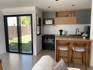 a kitchen with a counter and two chairs in it at Casa 6 personas con piscina en Piriápolis Playa los Angeles in Piriápolis