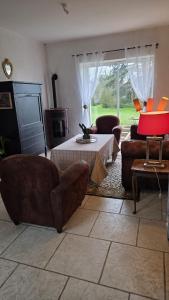 a living room with a couch and a table and chairs at Petit Gîte à la campagne in Brains-sur-Gée