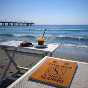a picnic table with a drink on the beach at Molo di Alassio Luxury Room in Alassio +2 photos