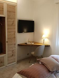a bedroom with a desk with a television on the wall at da Tony home B&B in Tarzo