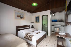 a bedroom with two beds and a desk and a shower at Pousada Bob Pai & Bob Filho in Ilha do Mel
