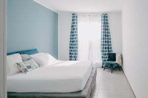 a white bed in a room with blue curtains at Domus Silvana Apartments in Ravenna