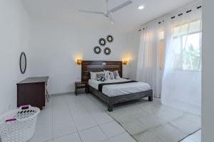 a white bedroom with a bed and a window at Wendy's Da-Azizi Homes Diani 2 in Diani Beach