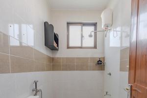 a bathroom with a toilet and a television on the wall at Wendy's Da-Azizi Homes Diani 2 in Diani Beach +26 photos