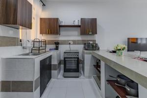 a kitchen with wooden cabinets and a stove top oven at Wendy's Da-Azizi Homes Diani 2 in Diani Beach