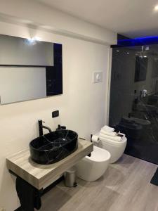 a bathroom with a black sink and a toilet at Sanu Home B&B in Lonate Pozzolo
