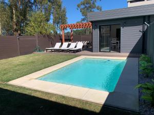 a swimming pool in a yard with chairs next to a house at Casa 6 personas con piscina en Piriápolis Playa los Angeles in Piriápolis