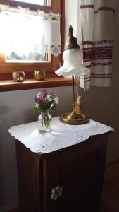 a lamp on a table with a vase of flowers at Budafai Vendégház in Kiscsehi