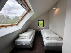 a attic room with two beds and a window at Vakantiepark De Kremmer in Gasselte
