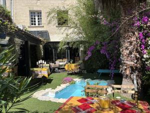 a garden with a table and chairs and a swimming pool at hôtel particulier d'hôte le Philippe-le-Bel in Villeneuve-lès-Avignon