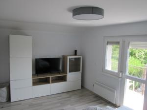 a white living room with a flat screen tv at ZÁMOR HOLIDAY HOUSE in Keszthely