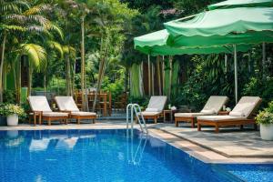 a pool with chairs and umbrellas next to a resort at FORTUNE HOTEL 2 LUCKY STAY Phu Quoc in Phú Quốc