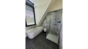 a bathroom with a shower and a tub and a sink at De Bosanemoon with Sauna | 6 persons in Gasselte +15 photos