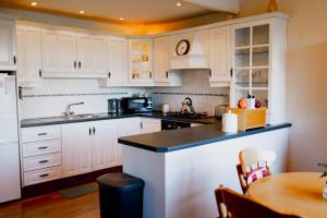 a kitchen with white cabinets and a wooden table at The Wild Atlantic Hideaway in Inch